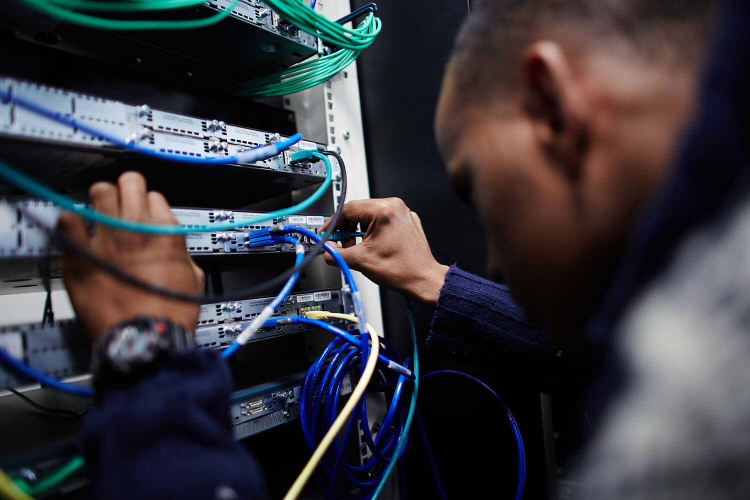 Ein Mann steckt Patch-Kabel an einem Serverschrank um.